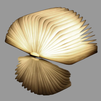 Lámpara libro abierta con luz cálida sobre una superficie de madera